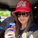 Kelly, enjoying her very American Budweiser in the parking lot while waiting for the bikes to show up.