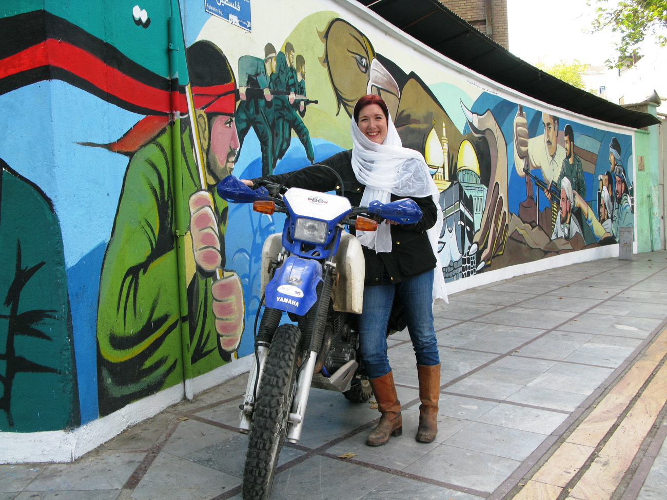 British travel writer Lois Pryce motorcycled 3,000 miles through Iran on her own. A mural on a military compound in Tehran's Felestin Square commemorates "The Imposed War," as the Iran-Iraq war is known locally.